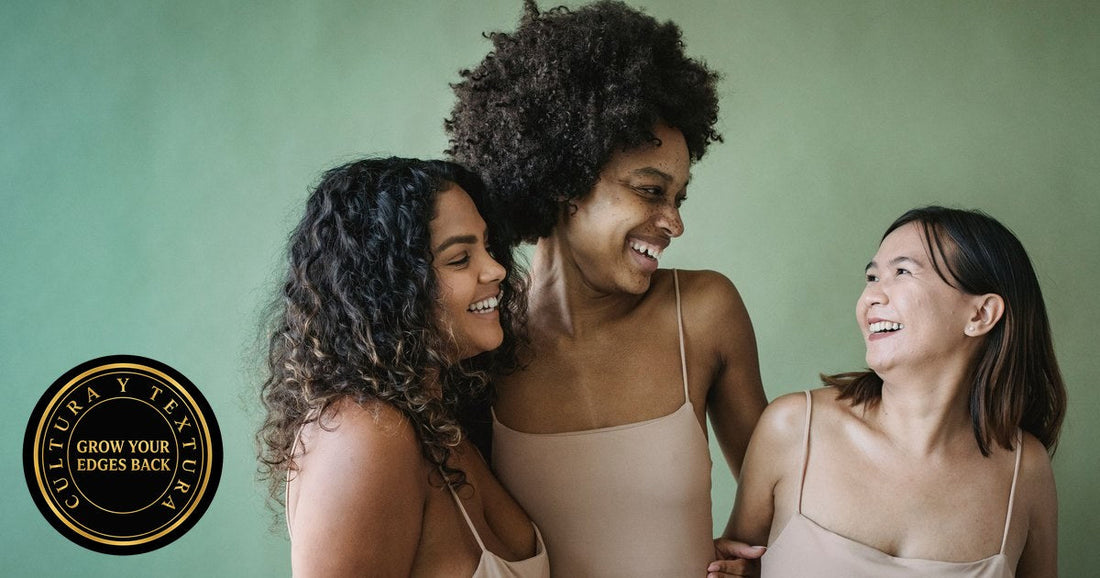 Three smiling women against a green wall, one with a full curly afro, one with long dark spiral curls and one with straight shoulder-length hair