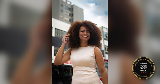 Woman with a full natural afro smiling outdoors in a city street, defined coils and a clean hairline