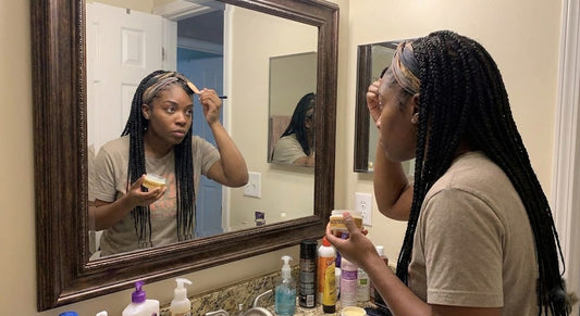 Black woman laying her edges at the bathroom mirror as part of her daily routine