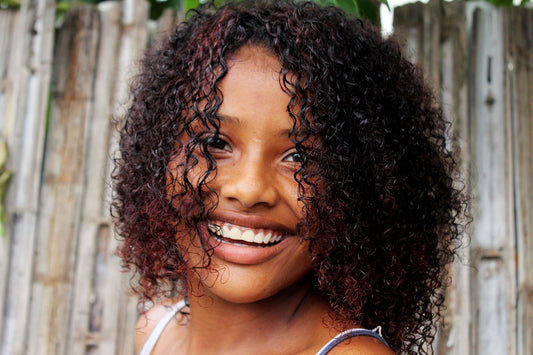 Mujer afrolatina con rizos definidos sonriendo al aire libre, Cultura y Textura de Grow Your Edges Back