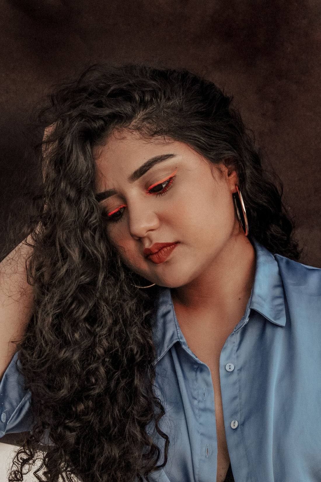 Latina woman with curly hair and hoop earrings