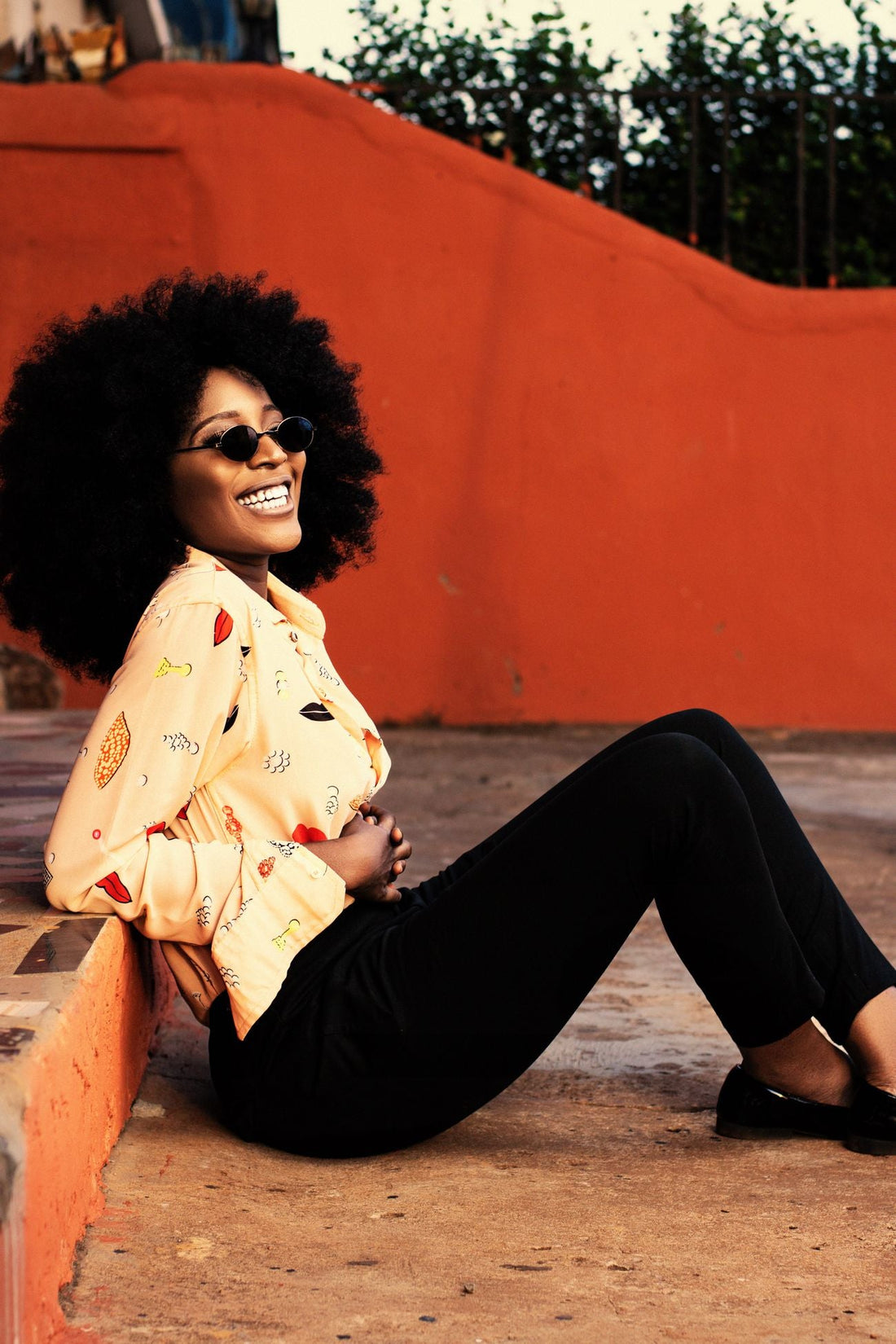 Black woman in sunglasses smiling outdoors in late summer light