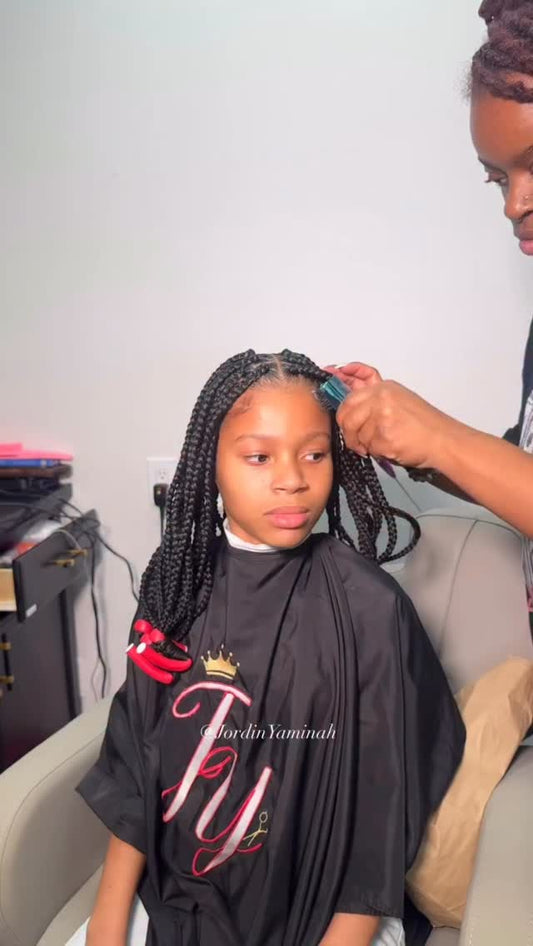 Long braids being installed during a protective styling session