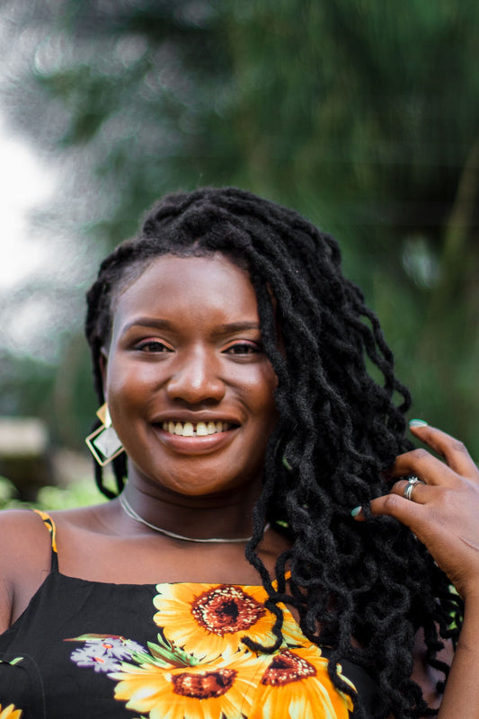 Black woman with long healthy locs smiling outdoors