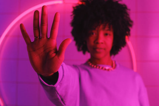 Black woman holding up her hand in a stop gesture under pink light