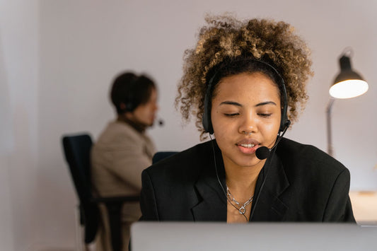 Black woman with curly hair wearing a work headset at her desk