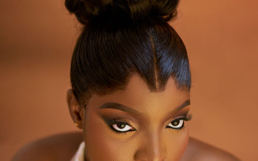 Black woman with a sleek top bun and a smooth, laid hairline with a center part