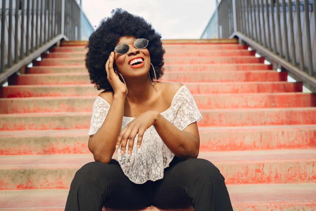 Joyful Black woman with a natural afro laughing, edge and scalp growth routine, Grow Your Edges Back